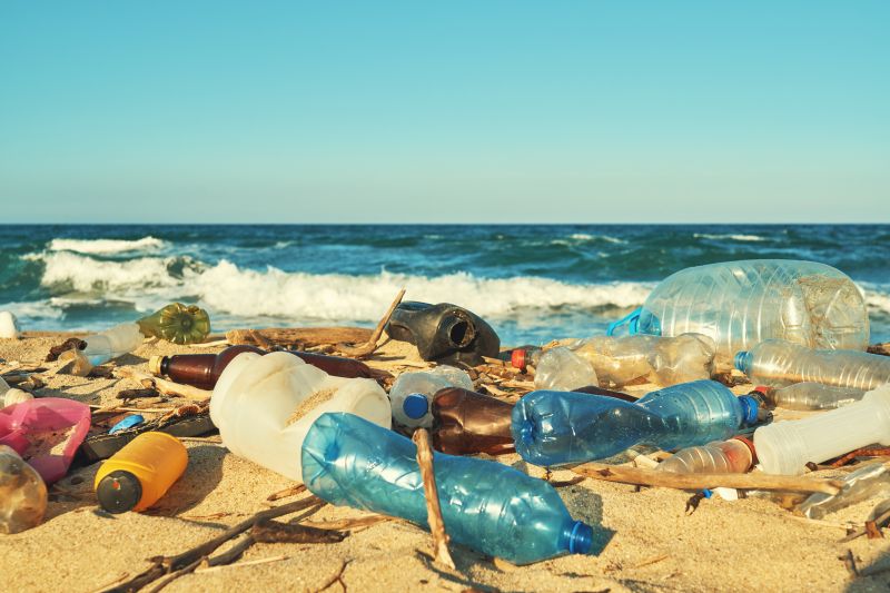 Sandstrand mit diversen, vom Meer angespülten Plastikabfällen